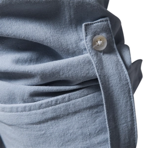 Close-up of light blue cotton shirt cuff featuring a white button and fine fabric texture