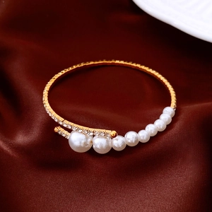 Close-up of elegant gold open cuff bracelet with gradient pearls and crystal rhinestones