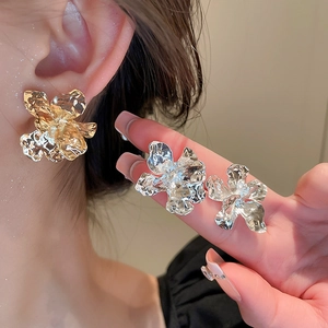 Detail view of gold and silver irregular metallic flower earrings shown on a model