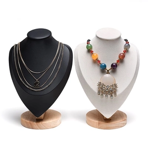 Detail view of black matte and beige velvet necklace display busts with round wooden bases
