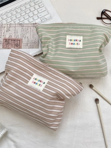 Portable striped canvas cosmetic bags in green and brown on an organized desk