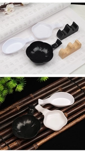 Detail of plastic ink dishes in flower and spoon shapes with wooden brush rests