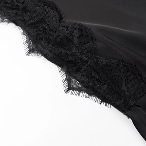 Détail macro de dentelle noire délicate sur une texture de tissu satiné lisse noir