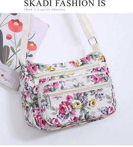 Close-up of floral crossbody bag with triple zippers and adjustable shoulder strap