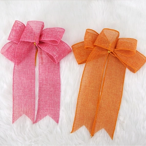 Flat lay view of colorful burlap bows in pink and orange on a soft plush white background