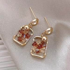 Vintage geometric gold earrings with amber faux stone and rhinestone accents on silk