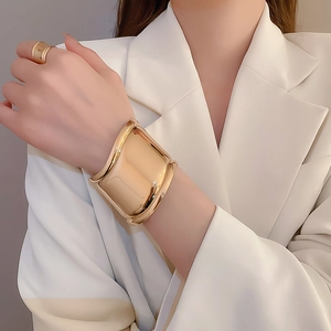 Macro shot of wide gold glossy cuff bracelet with a mirror finish on a female model