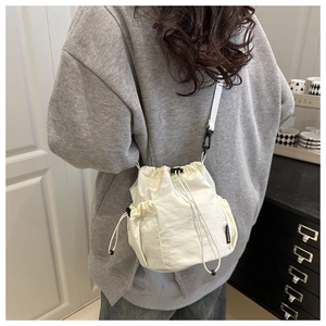 Detalle del bolso tipo saco de nailon blanco con cordón y etiqueta tejida 'FASHION'