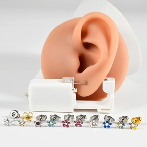 Macro detail of disposable piercing tool and 316L stainless steel flower earrings