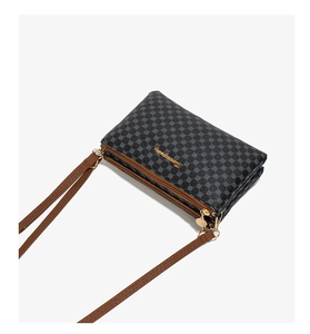 Detailed view of black polka dot crossbody bag with three golden zippers and brown strap