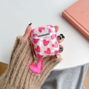 Detail of pearlescent shell pattern AirPods case with pink heart and matching charm