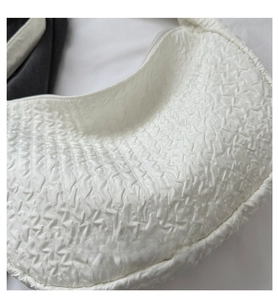 Detailed view of the elegant white half-moon bag featuring unique wavy pleated texture