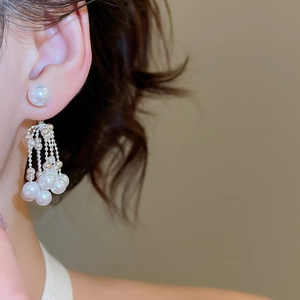 Close-up of a silver tassel pearl earring on a model featuring multiple small pearl chains