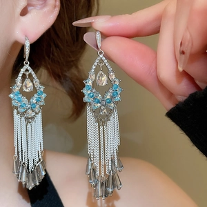 Macro view of crystal flower drop earrings with blue zircon and long tassel fringe