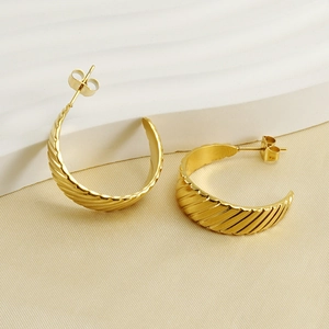 Detail of 18K gold-plated titanium steel ribbed hoop earrings on a textured fabric