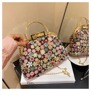 Detail of floral shell bag featuring gold metal handle and vintage clasp closure