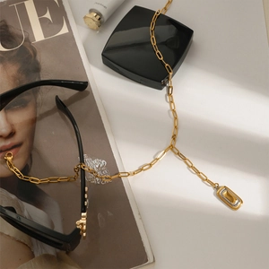 Flachbild der goldenen Büroklammer-Kette mit zweifarbigem Rechteck-Anhänger auf Lifestyle-Hintergrund