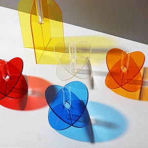 Detailed top view of geometric acrylic vases casting colorful shadows on white surface