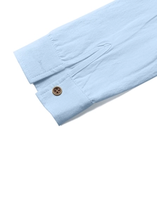 Détail du poignet d'une chemise bleu clair en coton et lin avec bouton marron