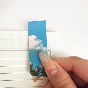 Magnetic cloud scenery bookmark holding pages on a lined paper notebook
