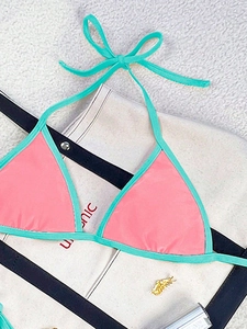 Detail view of pink halter bikini top with mint green contrast trim and tie straps