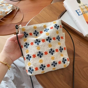 Gros plan de la broderie florale vintage sur un petit sac à bandoulière en lin blanc