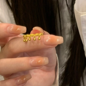 Close-up of a gold ring with round bead tassels worn on a finger for a chic look