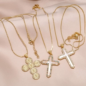 Elegantes collares de cruz dorados con circonitas y nácar sobre fondo de seda