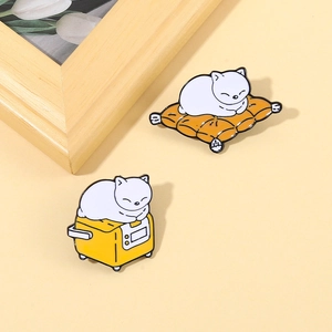 Detail of cartoon enamel pins featuring white cats on orange cushions and yellow toasters