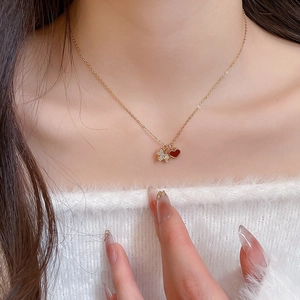 Gros plan du collier doré avec pendentif chiot en zircon et cœur rouge sur le cou