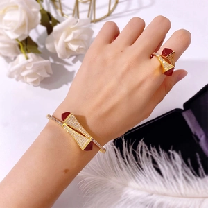 Detailed view of a gold double pagoda bracelet and ring set with red gems on a model's hand