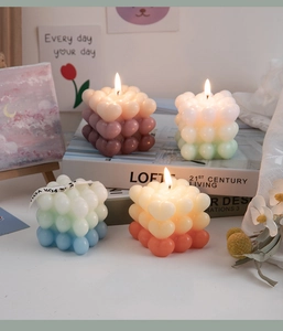 Detail showing colorful heart-shaped cube scented candles with warm flickering flames