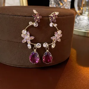 Elegant purple crystal flower drop earrings with gold finish on a velvet jewelry box