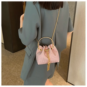 Detail of pink rhinestone bucket bag with golden ring handle and elegant tassel drawstring