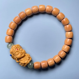 Detail of wooden bracelet featuring cylindrical beads and a carved Buddha head pendant