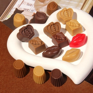 Handmade realistic resin chocolate charms in various shapes on a white heart tray
