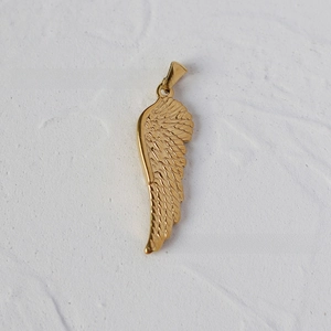 Detailed close-up of a 18K gold-plated wing pendant with fine feather textures