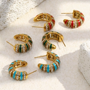 Détail de boucles d'oreilles en C dorées avec émail rouge, vert, bleu et zircons brillants