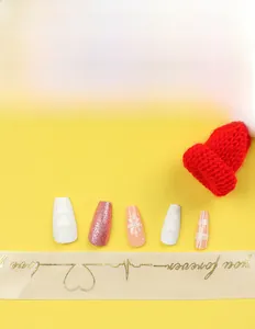 Detailed Christmas press-on nails with white heart relief, pink glitter, and snowflake art