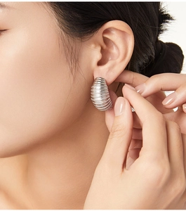 Close-up of geometric textured silver C-shaped earrings with spiral design on model