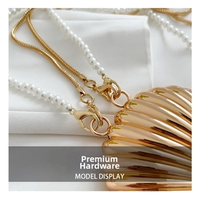Close-up of golden shell evening bag featuring pearl and metal chain strap details