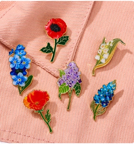 Detail of colorful enamel flower brooches on pink denim including lily and lavender