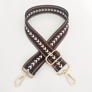 Close-up of adjustable dark brown nylon strap with white arrow pattern and gold metal hooks