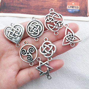Detailed close-up of seven silver Celtic knot alloy pendants held in a person's palm