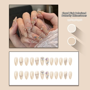 Detailed view of iridescent pink press-on nails with 3D butterfly crystals and chain accents