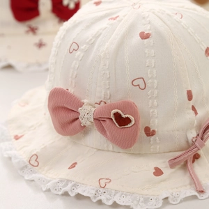 Baby sun hat with heart print, pink bow, and lace trim on cream cotton fabric