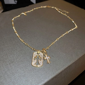Detail of gold cross pendant necklace with rhinestones on a textured grey box background