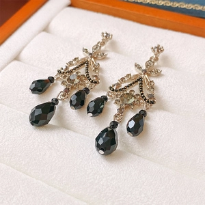 Detail of silver drop earrings with black rhinestones on a white velvet jewelry box