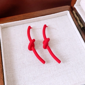 Macro shot of red matte knotted stud earrings placed inside a vintage wooden jewelry box