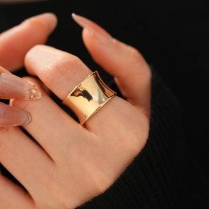 Close-up of a wide concave gold ring with a polished mirror finish on a hand